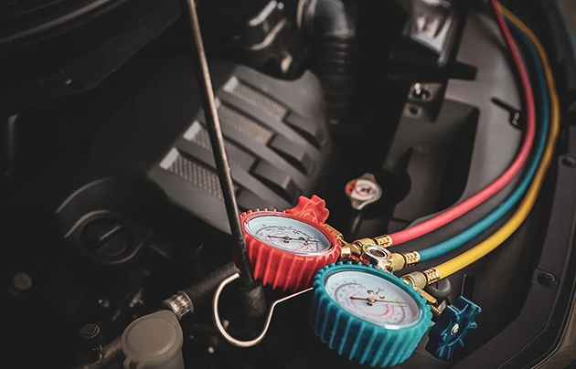 Car engine bay with colorful HVAC gauges attached.