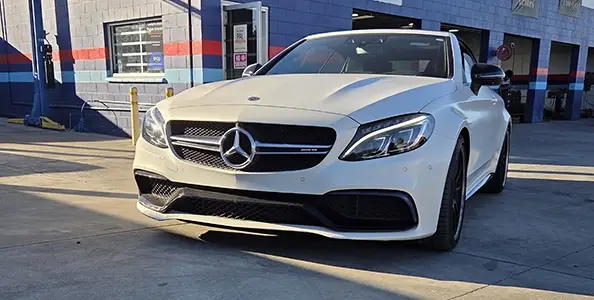 White Mercedes-Benz parked outside an auto repair shop.